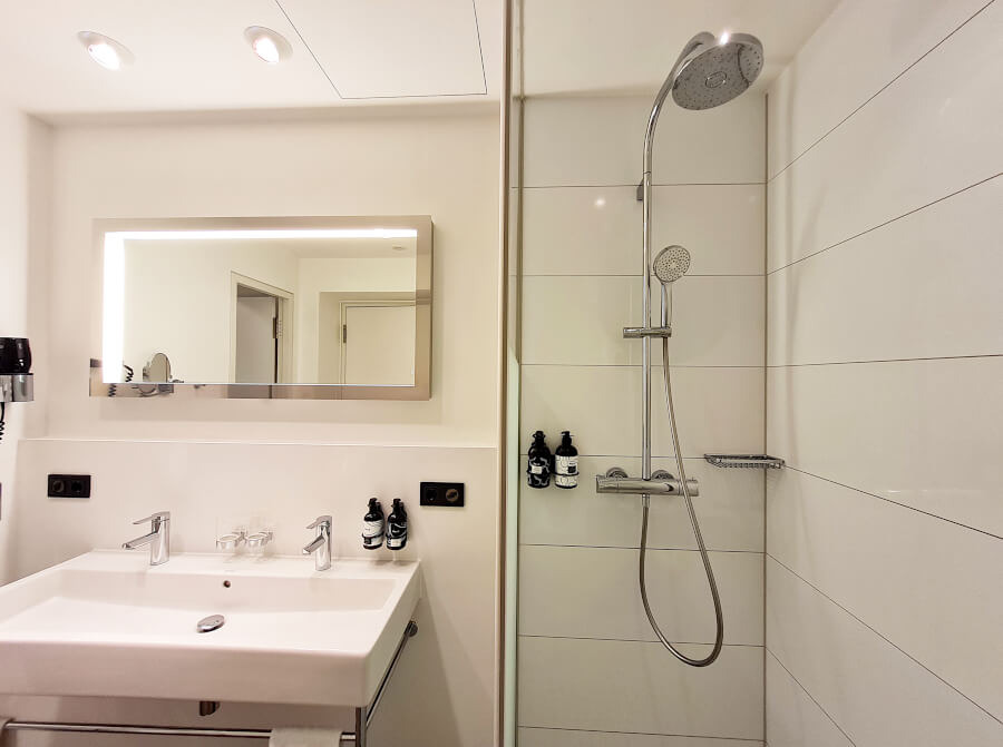 Begehbare Dusche mit Regenduschkopf im Badezimmer der Innside Lifestyle Suite