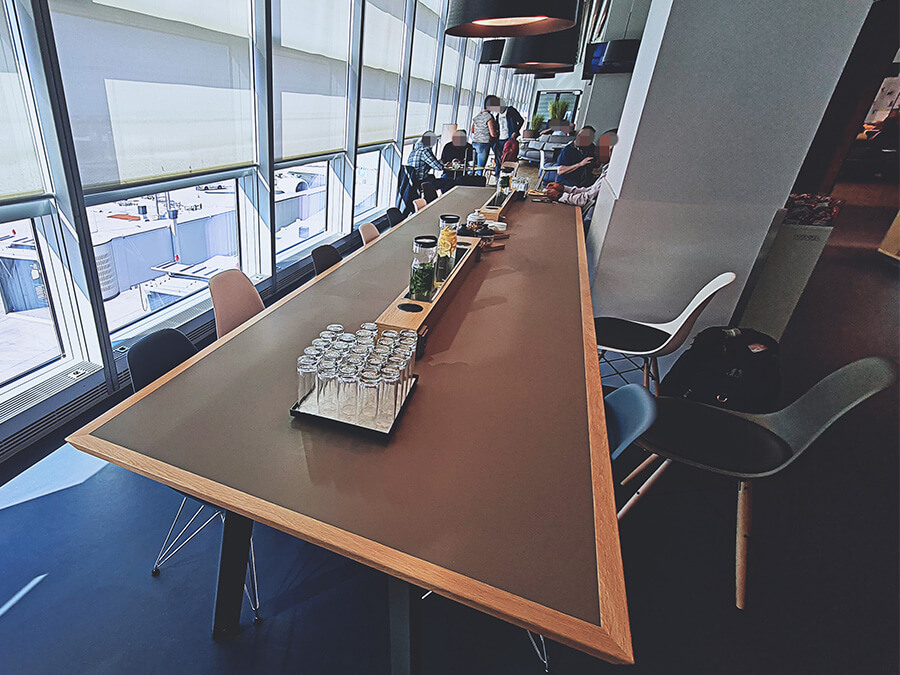 Lange Tische mit Infused Water in der Lufthansa Bistro Lounge